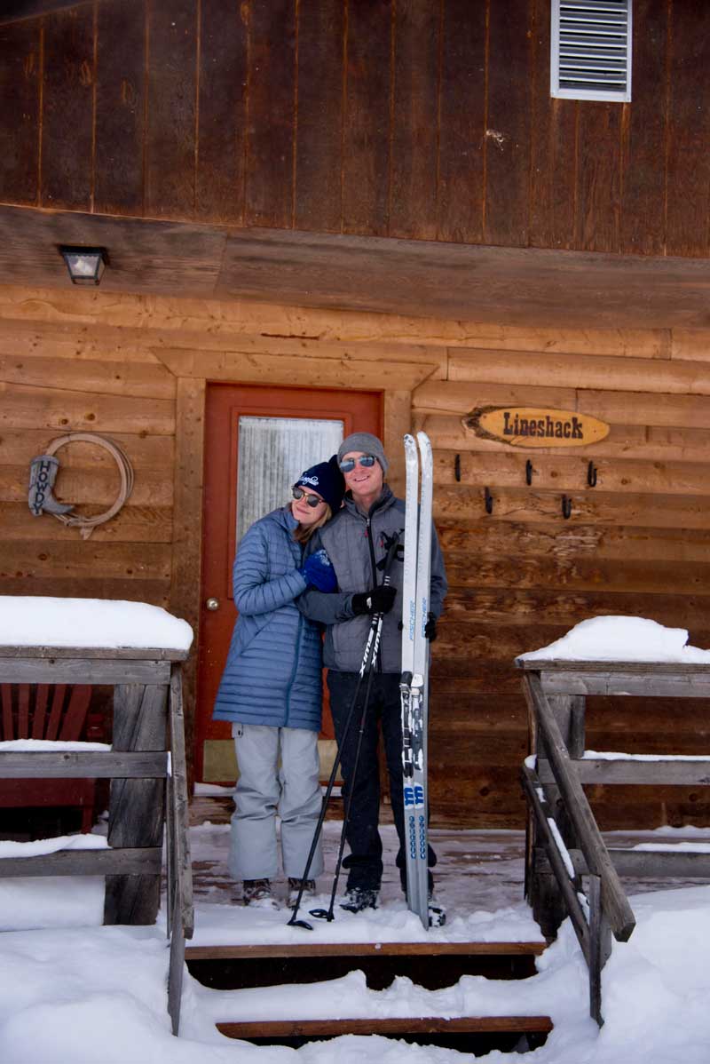 Two guests stand on the porch of a Latigo Ranch cabin before skiing