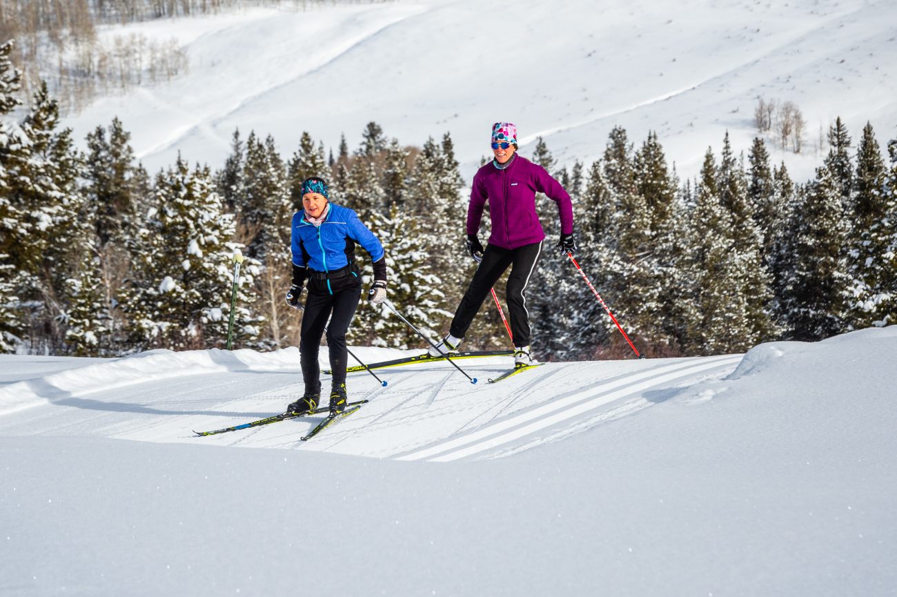 Two skiers smiling as they ski the trails at Crested Butte