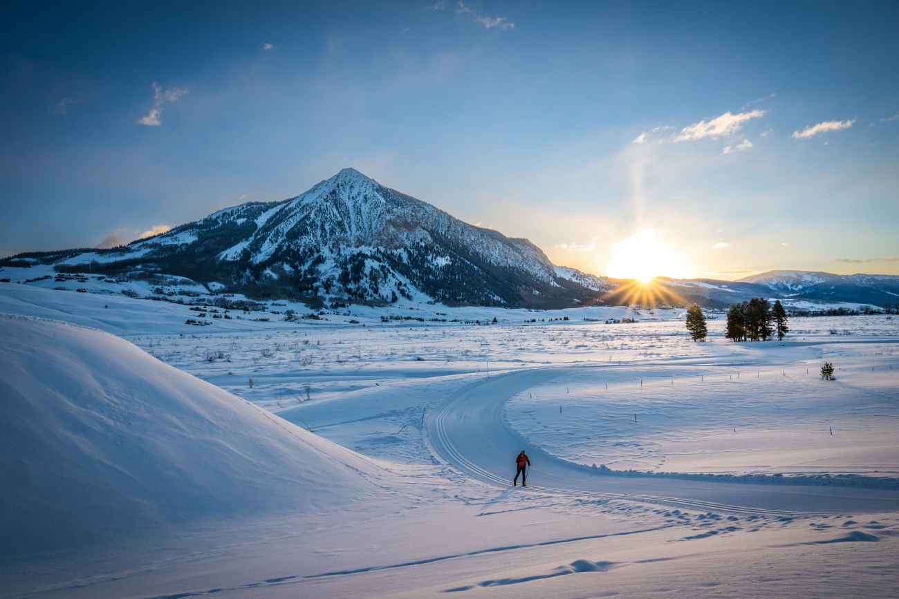 A single skier racing down the trail at Crested Butte with the sun setting in the background